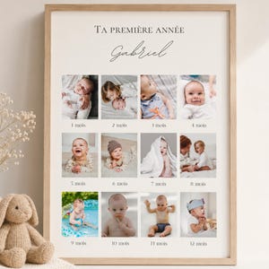 Peut inclure: Un cadre avec des photos de la première année d'un bébé, de 1 à 12 mois. Le texte "TA PREMIÈRE ANNÉE Gabriel" est en haut. Le cadre est marron clair, avec un lapin en peluche et un vase de fleurs au premier plan.