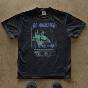 Puede incluir: Una camiseta gris carbón de manga corta con un estampado gráfico de la película Re-Animator. El diseño incluye un científico en un laboratorio, el texto RE-ANIMATOR y pequeñas escenas de la película con el pie de foto Herbert West has a very good head on his shoulders.