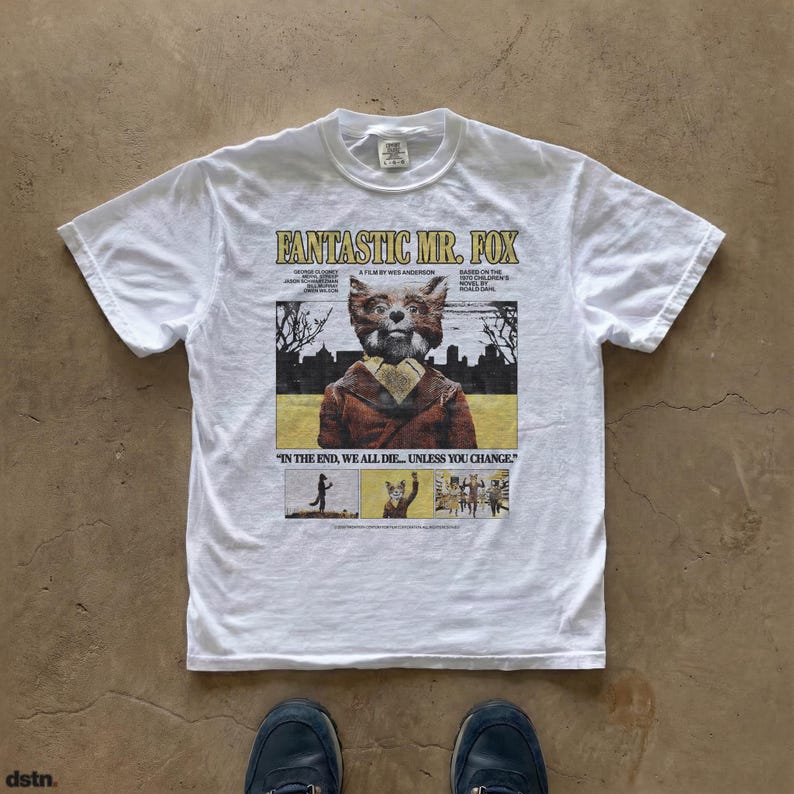 White t-shirt featuring a graphic from the movie "Fantastic Mr. Fox." The design includes the film's title, a portrait of the fox character, and the quote "In the end, we all die... unless you change."