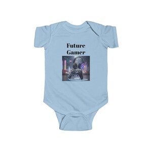 May include: Light blue baby bodysuit with the text "Future Gamer" above an image of a gaming headset and controller. The image has a neon-lit background. The bodysuit is made of soft material.