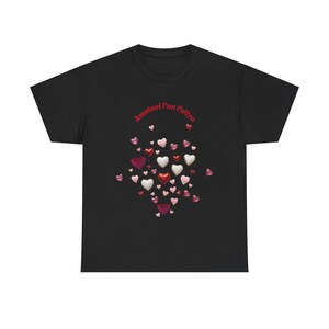 May include: Black t-shirt featuring a cluster of heart-shaped designs in shades of red, pink, and white. The text "Amatevi l'un l'altro" is arched above the hearts in red. The shirt is a casual wear item.