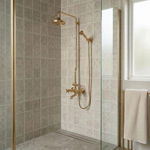 May include: A gold-toned shower system featuring a fixed overhead shower head, a handheld shower wand with a flexible hose, and a wall-mounted faucet with cross-style handles, all installed against a wall of light gray patterned square tiles.