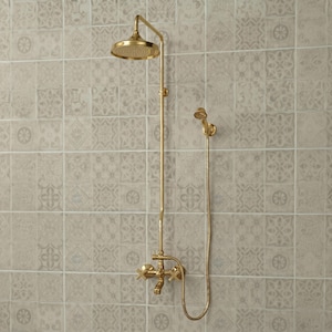 May include: A gold-toned shower system featuring a round overhead shower head, a vertical pipe, a handheld shower head attached by a flexible hose, and a wall-mounted faucet with two cross-style handles for controlling water flow and temperature.