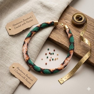 May include: A handwoven beaded necklace with green, orange, and white patterns. The necklace is displayed with a measuring tape, small beads, and tags that read "Handwoven Beadwork | Created with Passion."