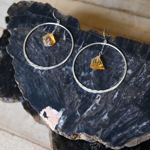 May include: A pair of silver hoop earrings with a dangling amber stone on each earring.
