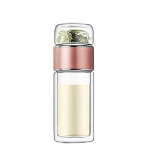 May include: A clear glass tea infuser bottle with a rose gold band. The top section holds loose tea leaves, while the bottom section contains a light yellow liquid. The bottle is designed for steeping tea on the go.