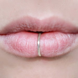 Human lips wearing a thick silver fake lip ring