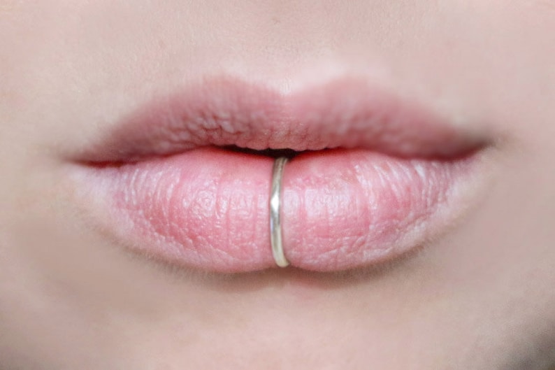 Human lips wearing a thick silver fake lip ring