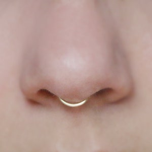 close up of human nose wearing a 14k gold peakabo septum cuff  by Curly Cuffs