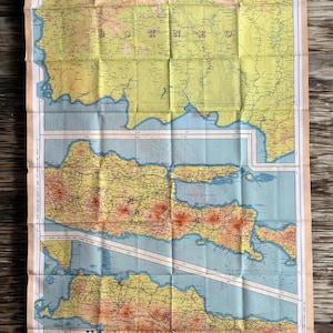 Puede incluir: Un mapa antiguo plegado de Borneo, Sumatra y Java, con detalles geográficos. El mapa utiliza colores amarillo, naranja y marrón para las masas terrestres y azul para los mares. El texto incluye "BORNEO" y "JAVA".