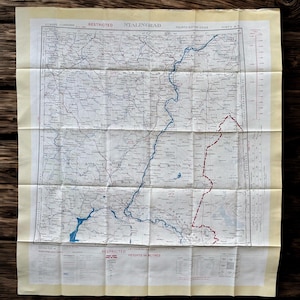 Puede incluir: Un mapa antiguo de Stalingrado, con detalles geográficos, ríos azules y fronteras rojas. El mapa está plegado y tiene el texto "EUROPE 1:1000000" en la esquina superior izquierda. El mapa está sobre una superficie de madera.