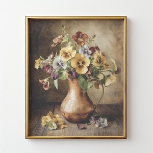 May include: A framed print of a still life featuring a copper pitcher filled with colorful pansies. The flowers are yellow, purple, and white. The pitcher sits on a wooden surface, with a soft, neutral background.