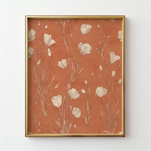 May include: Framed artwork featuring a floral design. The print showcases white flowers and stems against a terracotta background. The artwork is enclosed in a gold-colored frame, adding a touch of elegance to the botanical theme.