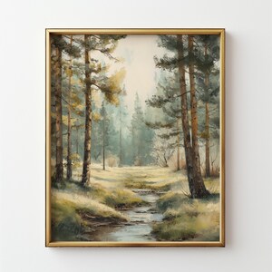 May include: A framed landscape painting depicts a serene forest scene. Tall, slender trees with green and yellow foliage line a small stream. The artwork is framed in a gold-colored rectangular frame, creating a classic aesthetic.