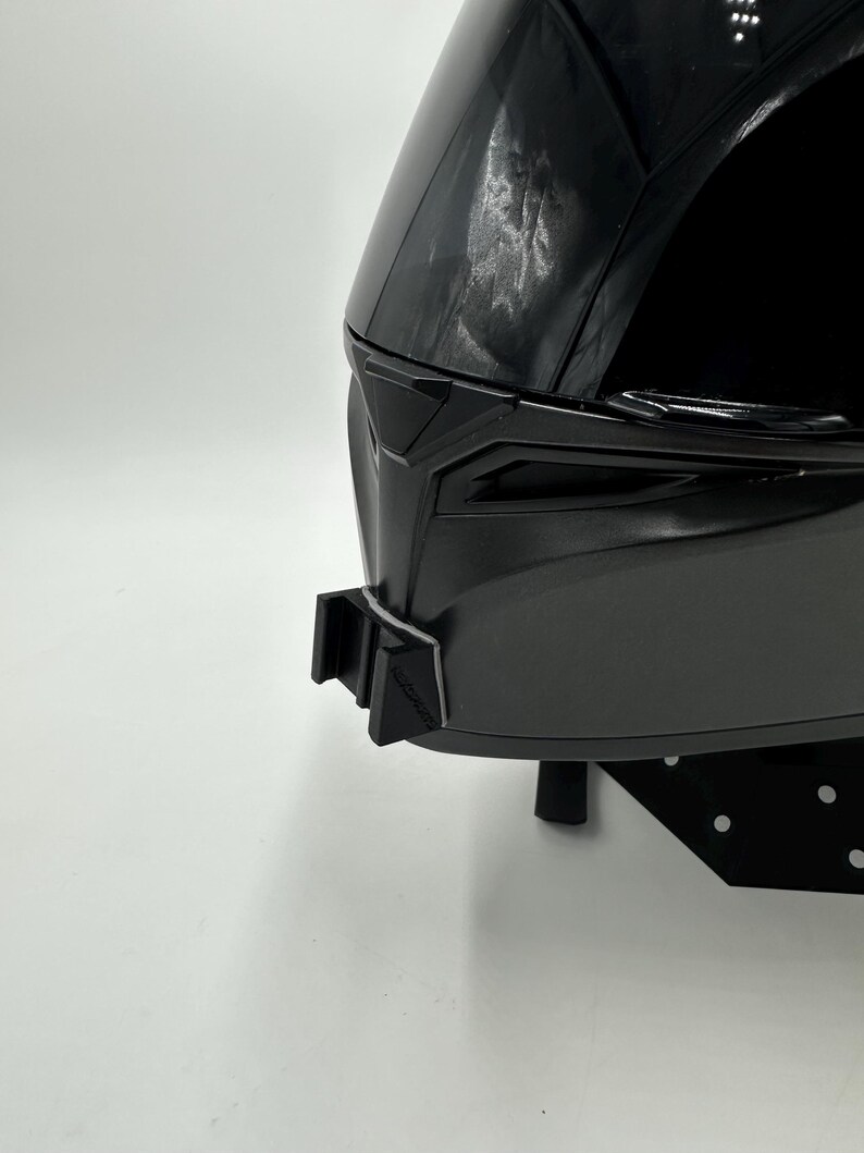 May include: A black motorcycle helmet with a glossy finish. The helmet has a sleek, aerodynamic design with a dark visor and a chin strap. The helmet is designed for safety and protection.