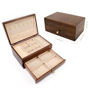 May include: A dark brown wooden jewelry box with a rectangular shape. The box is open, revealing multiple compartments lined with beige fabric. The box has a drawer and a lid with hooks for necklaces. The dimensions are 11.42 inches long, 7.48 inches wide, and 5 inches high.