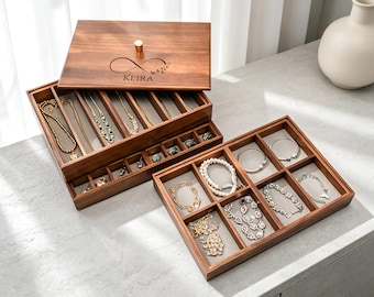 May include: A wooden jewelry box with multiple compartments, filled with necklaces, bracelets, and rings. The box is open, revealing the organized storage. The lid is engraved with the name "Keira" and an infinity symbol.