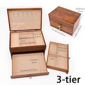 May include: A 3-tier wooden jewelry box with a dark brown finish. The box has multiple compartments and drawers, including ring holders and storage spaces. Dimensions are provided in inches and centimeters.