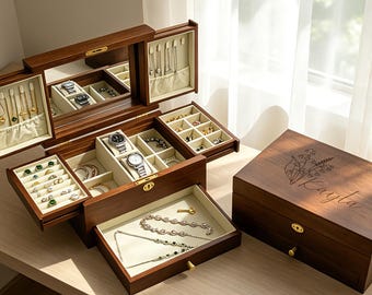 May include: A wooden jewelry box with multiple compartments, including a mirror and drawers. The box is open, displaying various jewelry items like rings, bracelets, and necklaces. A closed box with the name "Kayla" is also visible. The wood has a warm, brown tone.