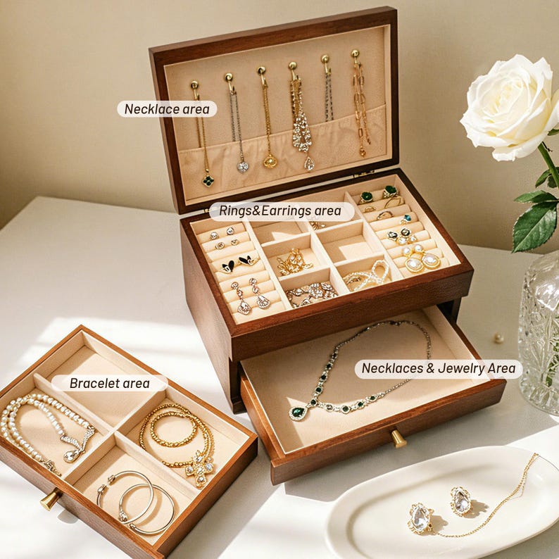 May include: A wooden jewelry box with multiple compartments for necklaces, rings, earrings, bracelets, and other jewelry. The box is open, revealing various pieces of jewelry. The interior is lined with a beige fabric.