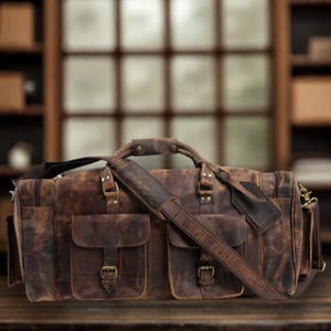 May include: A distressed brown leather duffel bag with multiple pockets and a shoulder strap. The bag features a top handle and metal hardware. The leather has a worn, vintage appearance, suggesting durability and a classic style. Ideal for travel or everyday use.