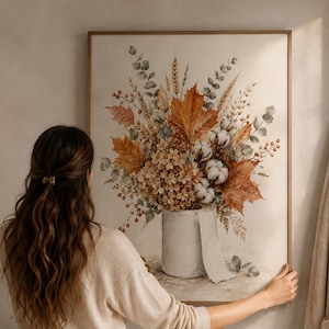 Könnte beinhalten: Ein rechteckiger Wandkunstdruck mit einem Blumenstrauß aus Herbstblättern, getrockneten Gräsern und Baumwollblüten, arrangiert in einer Vase aus einer Toilettenpapierrolle. Das Kunstwerk zeigt warme Orange-, Braun- und Grüntöne.