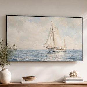 May include: A rectangular wall-mounted television displaying a painting of a white sailboat on a blue ocean under a cloudy sky. The television has a thin black frame and is positioned above a long wooden media console with slatted cabinet doors.