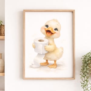 Könnte beinhalten: Ein gerahmter Aquarelldruck eines fröhlichen gelben Entchens, das eine Rolle Toilettenpapier hält. Das Entchen hat einen offenen Schnabel und steht vor einem hellen Hintergrund. Der Druck ist in einem hellen Holzrahmen, passend für ein Badezimmer oder Kinderzimmer.