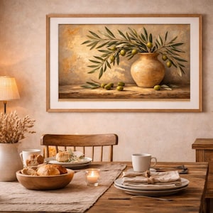 Könnte beinhalten: Ein Esszimmer mit einem Holztisch, der für eine Mahlzeit gedeckt ist. Ein gerahmtes Gemälde von Oliven in einer Vase hängt an der Wand. Eine Lampe, eine Vase mit Weizen und Geschirr vervollständigen die warme, einladende Umgebung. Rustikales Ambiente.