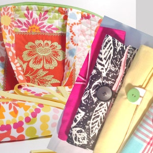May include: A colorful floral fabric tote bag with a yellow handle and a set of four fabric napkins with buttons. The napkins are in black and white, yellow, and pink and white stripes.