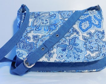 May include: A blue and white paisley patterned crossbody bag with a denim strap and buckle closure.