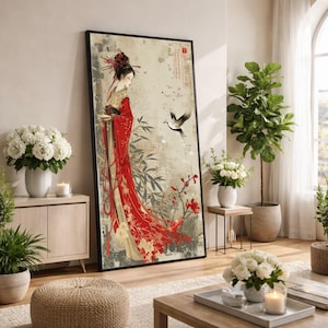 Può includere: Una stampa artistica incorniciata raffigurante una geisha in un kimono rosso con dettagli floreali e di uccelli. L'opera d'arte ha un'estetica vintage con uno sfondo neutro, bambù e un uccello in volo. La stampa è esposta in un soggiorno.