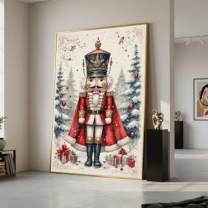 Op de afbeelding: Een ingelijste print van een kerstnotenkrakersoldaat. Het kunstwerk toont een gedetailleerde illustratie van de notenkraker in een rode jas en zwarte laarzen, tegen een besneeuwde bosachtergrond met cadeaus.