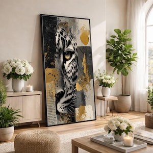 May include: A framed art print featuring a close-up of a leopard's face. The artwork is a mix of black, white, gray, and gold, with a textured, abstract background. The leopard's eye is a focal point, with a striking yellow iris.