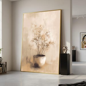 May include: Large framed artwork featuring a sepia-toned painting of a potted plant with long, slender leaves. The artwork has a gold frame and is displayed in a modern interior setting. The painting's neutral colors complement the room's decor.