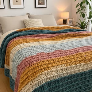 May include: A colorful, striped crochet blanket in shades of teal, gold, pink, and cream. The blanket is draped over a bed, showcasing its textured, handmade appearance. The design features horizontal stripes, adding a cozy and inviting aesthetic.
