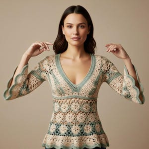 May include: A cream-coloured crochet top with a V-neckline and long sleeves. The top features a floral pattern on the bodice and is trimmed with a light green colour. The sleeves have a scalloped edge.
