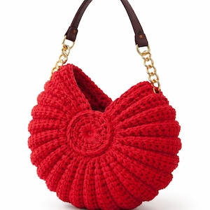 Könnte beinhalten: Eine leuchtend rote, handgehäkelte Handtasche mit einem einzigartigen, muschelartigen Design. Die Tasche hat einen braunen Ledergriff und goldfarbene Kettenriemen. Das zentrale Designelement ist ein kreisförmiges, strukturiertes Muster.