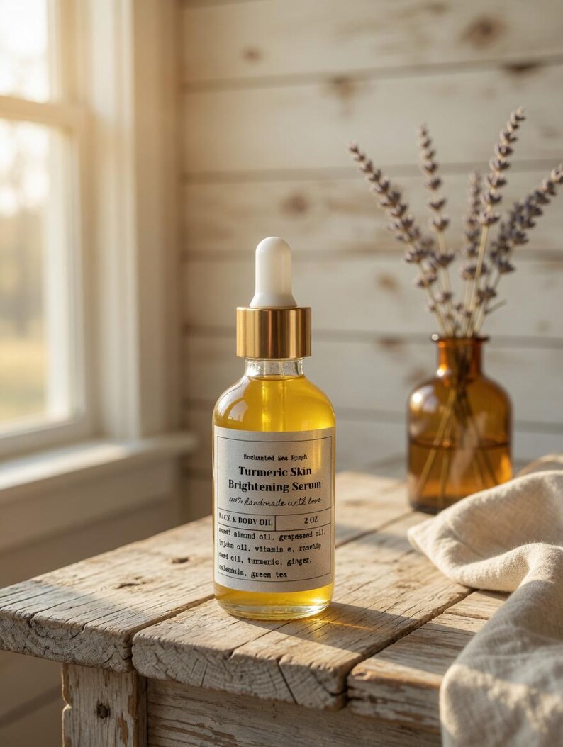 May include: A clear glass bottle of Turmeric Skin Brightening Serum with a gold dropper top sits on a rustic wooden table. The label reads "Enchanted Sea Nymph" and "Face & Body Oil." A small brown vase with lavender and a linen cloth are in the background.