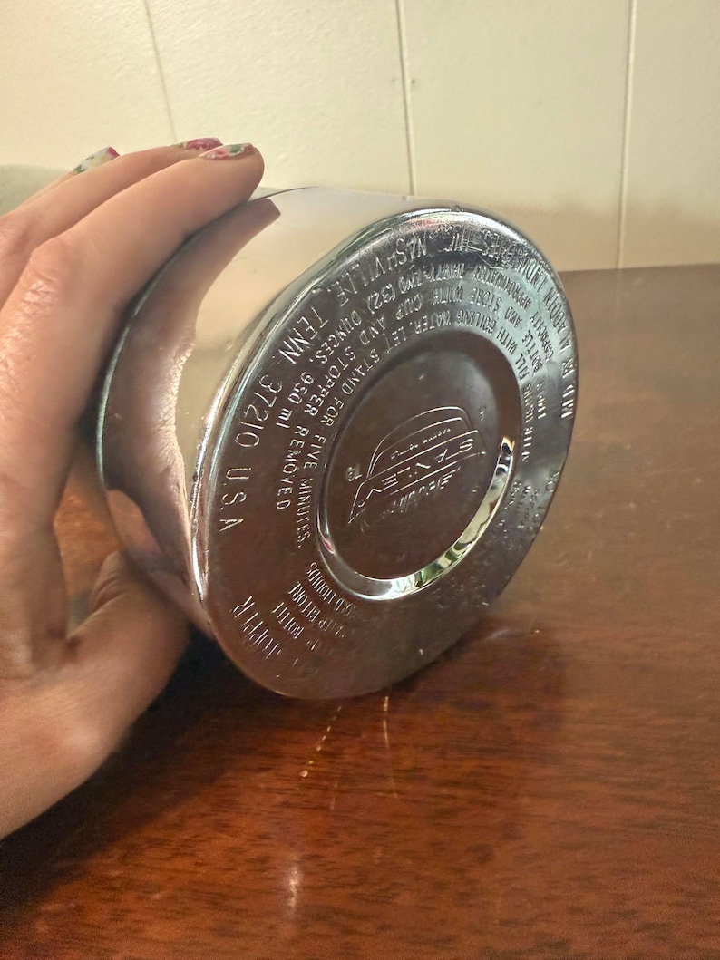 Puede incluir: Termo de metal plateado con un logotipo en blanco y negro que dice "Savlev". El termo tiene instrucciones de uso impresas en la parte inferior, incluyendo "Dejar reposar durante cinco minutos, quitar el tap&oacute;n y verter".