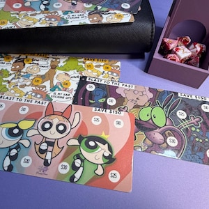May include: A black wallet and several colorful cards featuring cartoon characters and the text "BLAST TO THE PAST" and "SAVE $150". A purple box with pink and white items is also present.