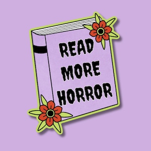 K&ouml;nnte beinhalten: Ein Aufkleber mit einem hellvioletten Buch mit dem Text "READ MORE HORROR" in Schwarz. Das Buch ist gr&uuml;n umrandet und hat zwei orangefarbene und rote Blumenakzente.
