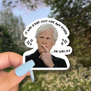 May include: A white sticker featuring a man with white hair and a finger on his lips. The sticker has the text "IT WAS A DAY JUST LIKE ANY OTHER...OR WAS IT?" in a speech bubble design with star accents.