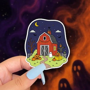 May include: A Halloween-themed sticker featuring a red barn under a starry night sky with a crescent moon. The sticker includes pumpkins, a scarecrow, and a ghost, evoking a spooky autumn scene. The sticker is held by a hand with a light blue nail.