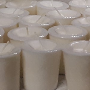 May include: A large group of white votive candles arranged in rows. The candles are in clear glass containers with a white wax interior.
