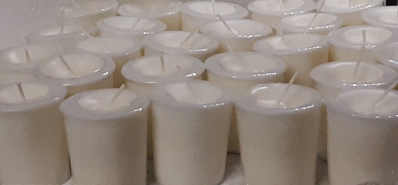 May include: A large group of white votive candles arranged in rows. The candles are in clear glass containers with a white wax interior.