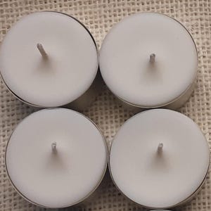 Puede incluir: Cuatro velas de t&eacute; blancas en recipientes de aluminio. Las velas son redondas y tienen una peque&ntilde;a mecha en el centro.