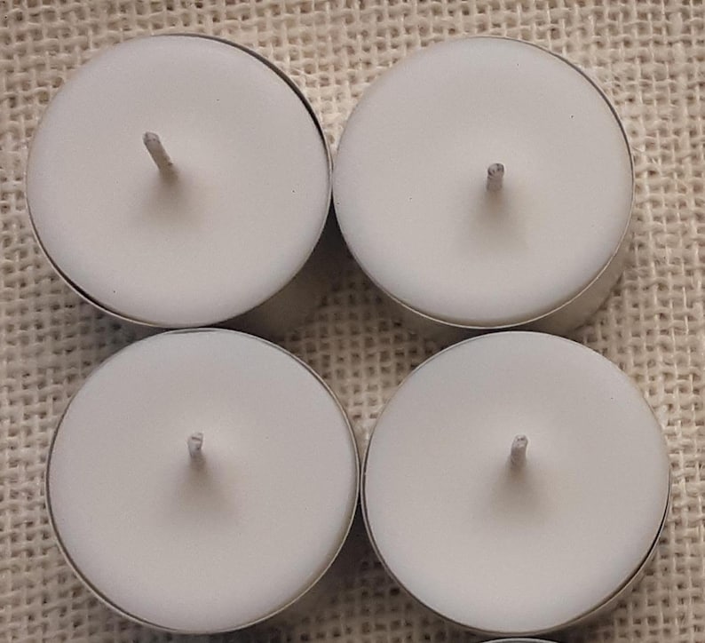 Puede incluir: Cuatro velas de t&eacute; blancas en recipientes de aluminio. Las velas son redondas y tienen una peque&ntilde;a mecha en el centro.