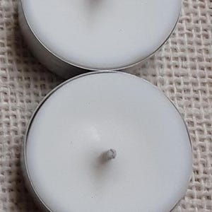 Puede incluir: Dos velas de t&eacute; blancas en portavelas plateados. Las velas son redondas y tienen una sola mecha en el centro.