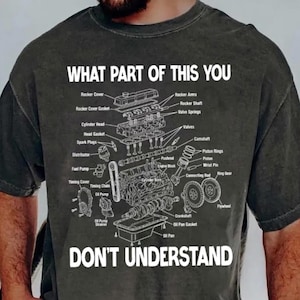 May include: A charcoal grey t-shirt featuring a white line-art diagram of an internal combustion engine with various parts labelled, including rocker cover, spark plugs, and oil pan, with the text WHAT PART OF THIS YOU DON'T UNDERSTAND.